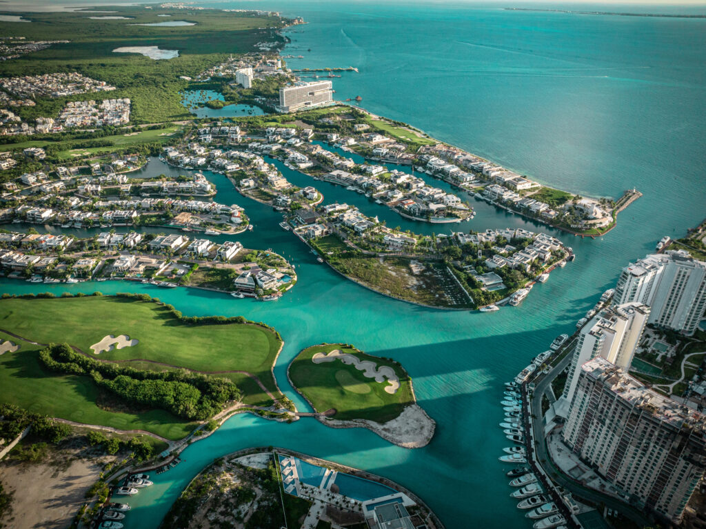 Coldwell Banker México muestra una vista aérea de la costa de la Riviera Maya con propiedades de lujo frente al mar y exuberante vegetación.